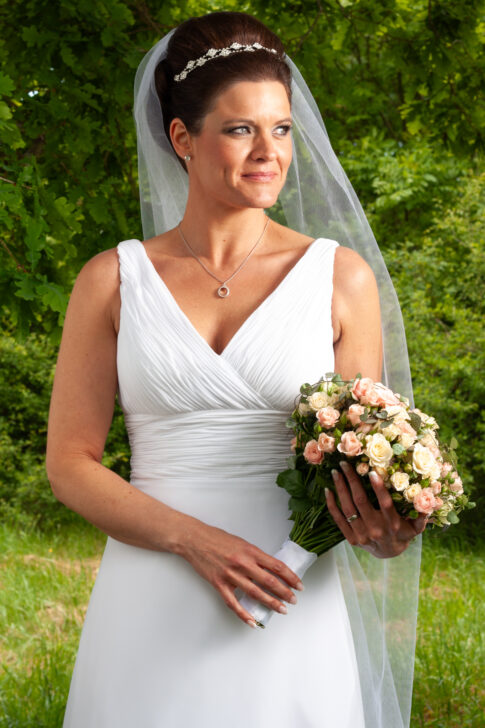 Bride in a white wedding dress holding a bouquet of flowers outdoors