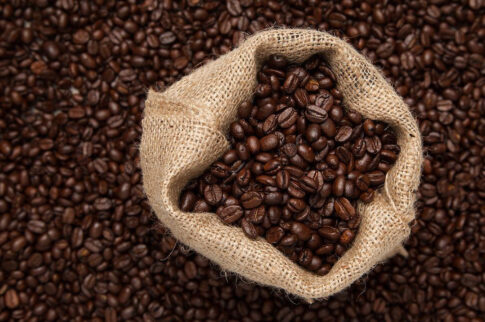 Coffee beans spilling from a burlap sack onto a wooden surface