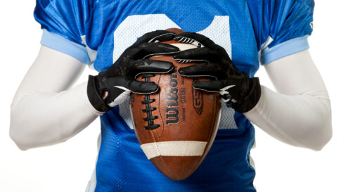 American football player holding a football in a blue Carlskrona Seahawks jersey