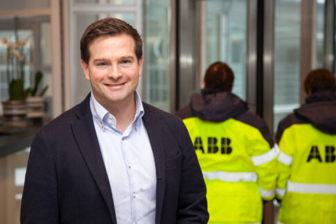 Businessman standing in an office with ABB employees in the background