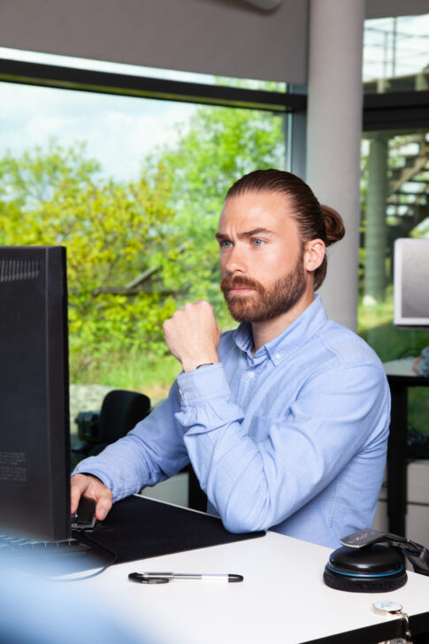 Businessman sitting at a desk in a modern office, photographed for Telenor.