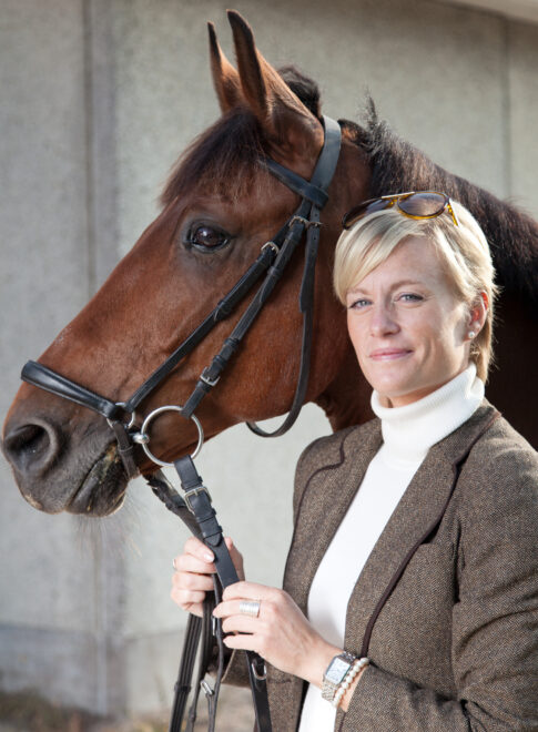 Woman standing beside a brown horse in an outdoor portrait