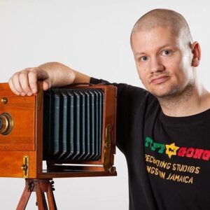Magnus Nilsson poserar bredvid en gammal bälgkamera i studio