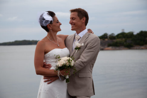Bride and groom standing together beside the water on their wedding day