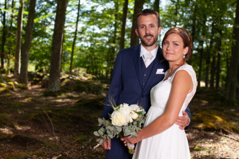 Bride and groom standing together in a green forest