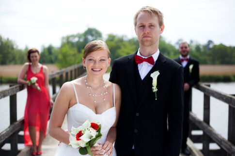 Bride and groom standing together on a wooden pier beside the water