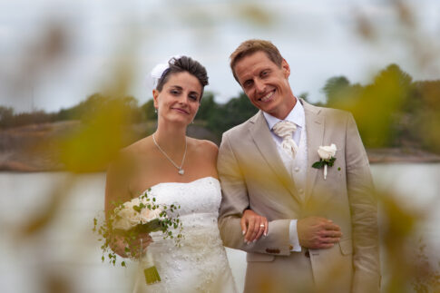 Wedding couple photographed through soft, out-of-focus foliage