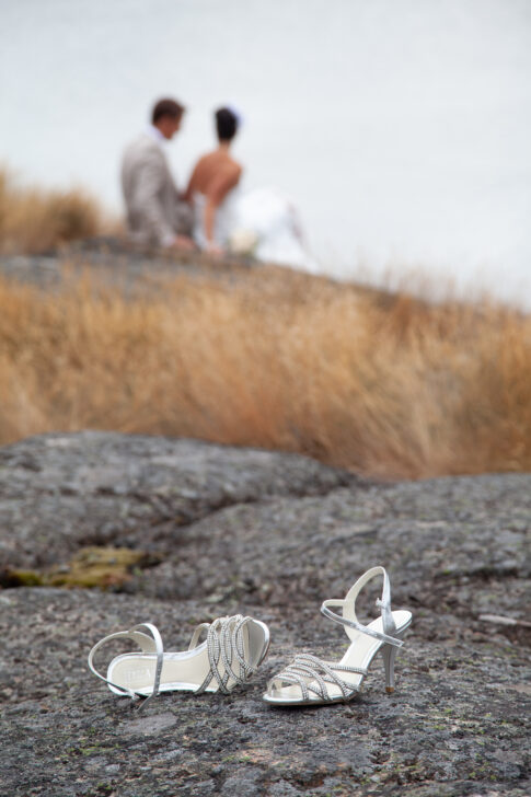 White wedding shoes placed on rocks beside the water